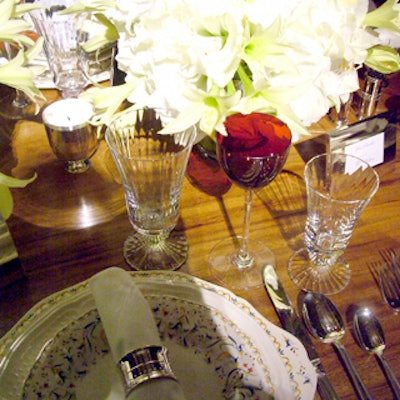 On the Darren Henault Interiors table, two plates—one floral-patterned, one plain white—topped each patterned charger, and red-tinted wine goblets alternated with clear etched glasses of varying sizes.