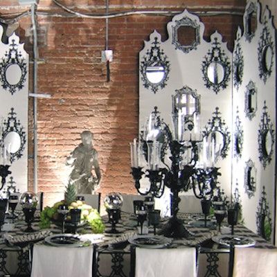 Michael Tavano created a fanciful black-and-white garden setting incorporating fabrics from F. Schumacher & Company. Mirrors filled in decorative frames on upholstered screens around the perimeter, and Tavano used black stemware, shiny gazing globes, and two elaborate antique Venetian glass candelabras on the table, which was upholstered with a black-and-white, knot-pattern fabric.