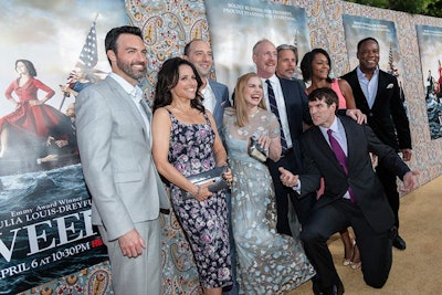The cast, including star Julia Louis-Dreyfus, posed in front of a heavily patterned step-and-repeat lined with posters for the show.