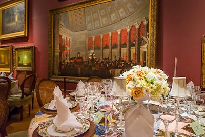 Simple white napkins and white-, yellow-, and marigold-colored flowers complemented the complex linen design without competing for attention.