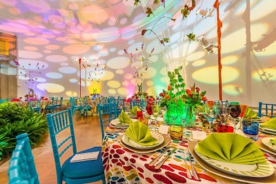 A rainbow of colors decorated the tables with multicolored linens, lime green and bright pink place settings and napkins, bright blue chairs, and yellow, blue, and red glasses.