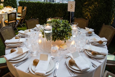 Table settings included traditional garden-style folding chairs and crisp, white linens, along with floating candles and greenery centerpieces. The menu included lobster salad, heirloom tomatoes and burrata, and herbed lamb with mustard sauce from Glorious Food.
