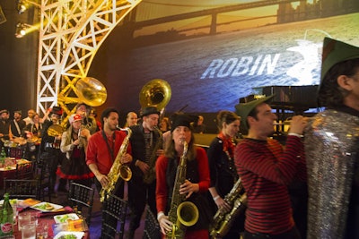 To signal the end of the cocktail hour, the Hungry March Band led a procession to the dining room. Some musicians wore Robin Hood costumes, while others danced and held signs that read, 'Follow Us' and 'It's Time to Eat.'