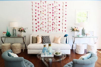 Pink flowers affixed to a wall with washi tape created a feminine backdrop within the Beverly Hills home that served as the event venue. The blossoms were arranged in columns by type, with, for example, calla lilies in one row and ranunculus in another.