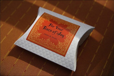 For a wedding reception, YourBash set chairs with personalized gifts for guests in the event's color palette: individually-wrapped and branded handkerchiefs labeled “for your tears of joy.” After the gifts served their purpose on the big day, guests took them home as favors.