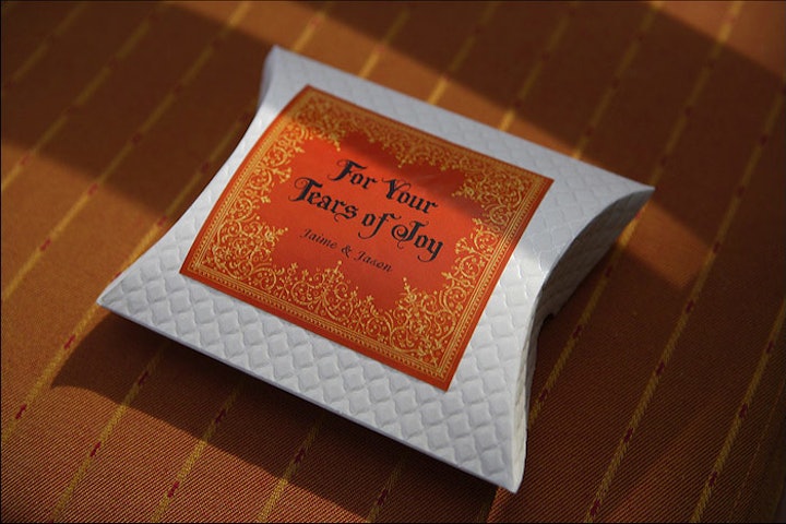 For a wedding reception, YourBash set chairs with personalized gifts for guests in the event's color palette: individually-wrapped and branded handkerchiefs labeled 