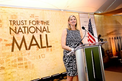 A stylized rendition of the Washington Monument was featured on the lectern, where Trust president Caroline Cunningham delivered remarks. The monument reopened last month after nearly three years of repairs needed to fix damage from an earthquake. A blueprint-style map of the mall formed the backdrop for the stage.