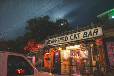 For a casual, offbeat place to entertain out-of-town clients, Mean Eyed Cat Bar reopened in October featuring a curated collection of clutter with an emphasis on all things Texas and Johnny Cash. A renovation and expansion added an outdoor bar, liquor cocktails, and a menu from Stubbs Bar-B-Q. The bar's signature 'Mean Juice' drink is silver tequila infused with fresh ghost pepper chilies that comes with a warning from bartenders about its potency. The bar is available for private events and holds 160 guests.