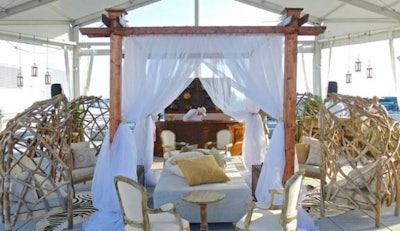 Safari camp-style lounge area with beautiful basket chairs and plush pillows surrounding a cabana bed with 11' tall dark cherry beams and white sheer draping.