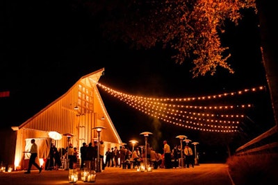 Swagged Italian Bistro Lights above guests at outdoor barn reception in Napa Valley, California.