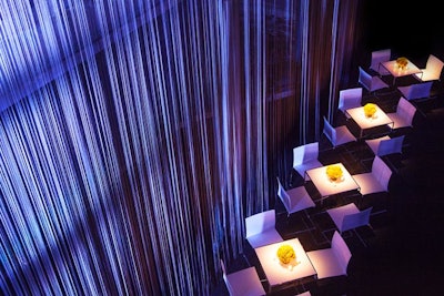 To transform the intimate venue without disrupting its existing infrastructure, the producers hung approximately 45,000 slate-tone strings from the mezzanine balcony via 40 uprights. These string drapes that surrounded the room created a backdrop that was light and easy for guests to pass through. The verticals were wrapped in a matching gray textile so as to blend in.