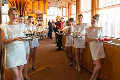 Cocktail waitresses dressed in matching white dresses greet guests with a flute of champagne