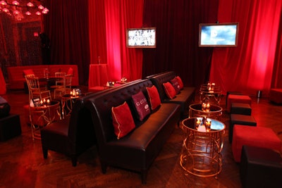 Enclosed in rich red drapes, the room held a variety of seating options, from semicircular red booths to comfy couches and ottomans; branded pillows in red and gold added to the look. Integrated into the layout were interactive food stations, including beef and turkey carving tables and sweet and savory pastries suspended from hooks.