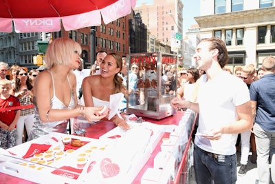 To celebrate the launch of DKNY's MYNY fragrance, the brand tapped Rita Ora and Chrissy Teigen to give fans heart-shaped pretzels—made by Cronut creator Dominique Ansel and a nod to the scent's similarly shaped bottle—from a branded cart stationed at Madison Square Park in New York on August 19.