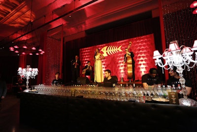 In contrast to the adjacent alley-inspired bar—and the police station set up at the entrance—the New York Public Library's third-floor room was marked by rich red lighting and decor, ornate lamps, beaded curtains, and handcrafted pillows. Much like Fish Mooney's bar in the show, the space also included a stage for performances, but rather than make the cabaret singer a focal point of the room, Abel McCallister placed the raised platform behind the bar so that it became more of a decor piece.