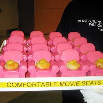 Tiny puff pastries made to resemble cushions sat on a tray of miniature pink armchairs.