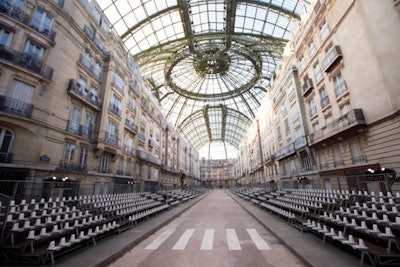 After last season's supermarket blitz, Karl Lagerfeld's Chanel show returned to the Grand Palais, this time with attendees entering into a streetscape 'Boulevard Chanel' to celebrate female—and fashion—power. For the September 30 event, Villa Eugenie built a 427-foot-long runway, flanked by façades soaring some 82 feet into the air that mimicked life-size Haussmannian buildings. Scaffolding across one façade supported the runway lights while 'standing room' guests were kept behind faux metal police barricades.