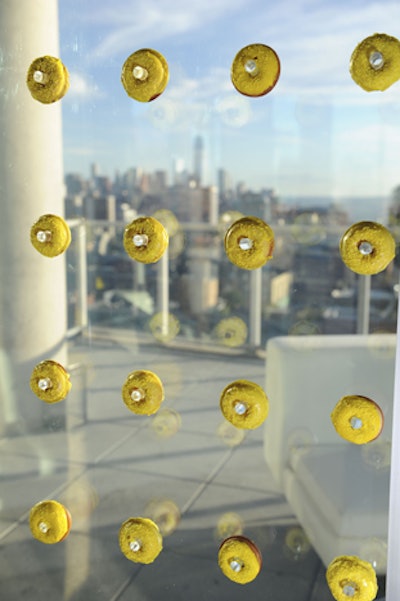 Bright yellow frosted donuts floated on a plexiglass display on the windows of the Glasshouses in New York City.