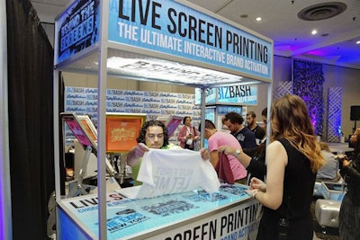 Attendees lined up for live screen T-shirt printing at Simon Elliot's booth on the expo floor.