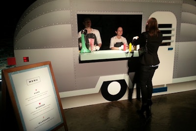 Next to the second clothing display was the other food station, a cutout of an Airstream-trailer-turned-diner-car intended to evoke traditional roadside Americana. On the menu were bite-size hot dogs in mini brioche buns with ketchup or mustard; porterhouse beef burgers with cheddar cheese; burgers made with a black bean patty and guacamole; and spiked milkshakes made with bananas, chocolate ice cream, and rum.