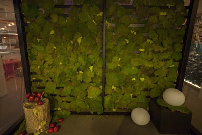 A moss-adorned wall served as the backdrop for the minimal white dining setup at the Coalesse and OEC Business Interiors vignette, which was designed by Solomon Cordwell Buenz.