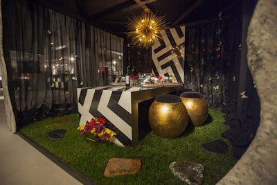 Bright accent flowers, a black-and-white-patterned table, and gold seating popped against the grass flooring at the Cambria display, which was designed by Fredman Design Group.