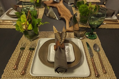 Feathers tucked into wooden napkin rings offered a subtle nature vibe at the dining table from Modern Luxury Interiors Chicago by Casa Spazio, which was designed by Interiors Spaces Inc.
