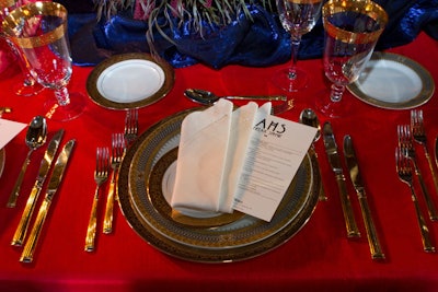 Heavily gilded table settings atop red linens made for an overstated, theatrical look.
