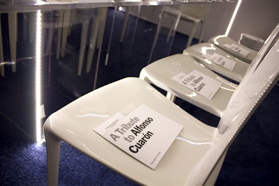 The dining space included a mix of round and rectangular Lucite tables, sleek white chairs, and indigo carpeting.