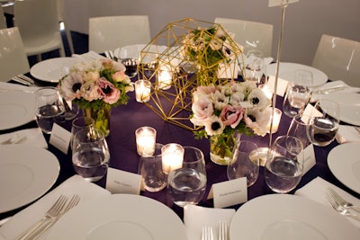 The table decor consisted of gold geometric pieces, along with bunches of pale flowers and a mix of tapered and votive candles.