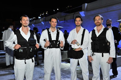 The waitstaff matched to the event's unconventional theme, donning white flight-inspired jumpsuits under utility vests, harnesses, and side packs from which the event's menu of foods were distributed.