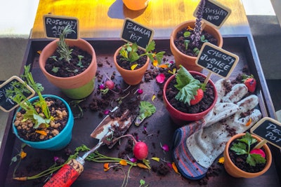 The Pot Pie Garden dessert from Barton G. LA features six individual pies (pecan, key lime, cherry jubilee, banana cream, rosemary apple, and Mississippi mud). Each pie is baked into an individual flower pot and topped with chocolate 'soil' and a sprig of fresh herb. Muddied (aka chocolate-stained) gardening tools and gloves complete the platter.