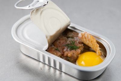The combination meal of wild salmon tartare, quail egg, horseradish emulsion, dill, and potato gaufrette is part of Love Catering's repertoire, but, according to owner Hermes Clausz, 'rendered completely new and different [served] in an anchovy tin that had to be pulled open.' Guests ('survivors') were given a stainless steel mini tool (sfork) and told it was 'essential to their survival' so they could eat different appetizers with it.