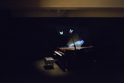 In collaboration with Fornasetti, Valentino devised a five-room installation entitled 'The Five Senses' that realized the senses of touch, sight, smell, taste, and sound. Representing sound was a grand piano placed in a blacked-out gallery space, with an animated projection of butterflies—a house code—on display.