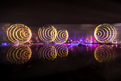 Large-scale lighted shapes and images, including spirals, were projected from the woods onto the venue's lake.
