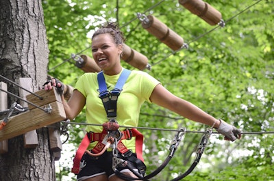 A climber enjoys a pause at a tree platform at The Adventure Park