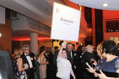 Tables were arranged in sections named after different genres of writing, such as romance, to help guests find their seats. After the cocktail hour, volunteers held large signs with the genre name to guide guests to dinner.