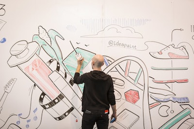 After getting sneak peaks of the day’s talks, visual artist Derek Cascio worked overnight to draw massive black and white murals of those themes onto the walls of the convention center with a dry-erase tool known as IdeaPaint. Then attendees added their own layers as the sessions got underway.
