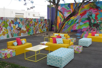 Custom yellow benches mixed with aqua patterned rectangle ottomans and floral side tables for event in Wynwood