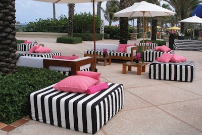 Black and white striped ottomans with lounge chairs and pink pillows for outdoor, poolside event
