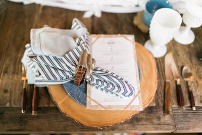 Also at the Tassels and Tastemakers event, place settings on a rustic tabletop included napkin rings made from vintage leather belts atop slices of tree branch. Mindy Weiss designed the table with milk glass from Borrowed Blu.