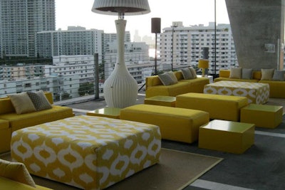 Custom yellow lounge with patterned ottomans and side tables for event in Miami Beach