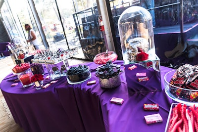 Sweets and decor at the dessert table kept with the red, black, and purple color palette.
