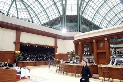 Sparing no expense for detail, Chanel even transformed the photographer's pit into a makeshift bar-like structure for uniformity of design. Flanked on both sides, and rimming the tiers of seating, were two rows of café-style tables where magazine editors in chief and celebrity guests sat.