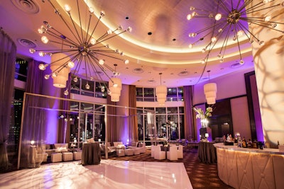 Sputnik chandeliers hang above a dance floor surrounded by a custom round bar and luxe lounge furniture at Trump Chicago
