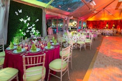 The design team chose a springtime color palette of pink, orange, green, yellow, and green for the linens, flowers, and lighting in the dinner tent.