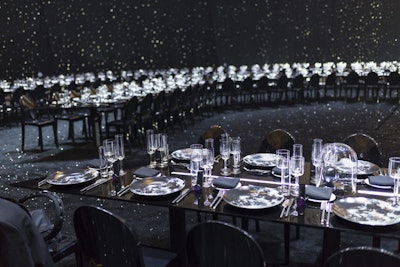 Guests dined above a custom floor covered with crushed rock and gravel that had been mixed with glitter to achieve a sparkle effect so as to add some pops of brightness to the otherwise all-black decor scheme.