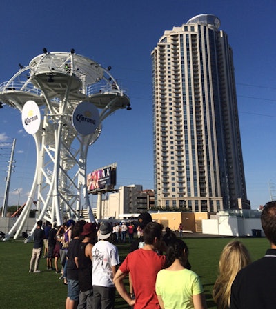 Attractions include a zip line, which sends guests soaring from a high-design platform. The white tower features curving lines, as well as round logos from sponsor Corona.