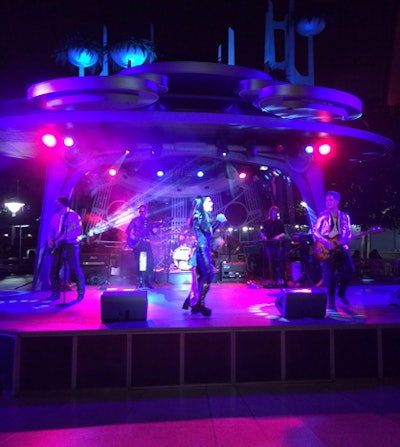 Musicians in futuristic costumes entertained guests in front of a stage positioned near the dining tables within Tomorrowland.
