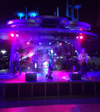 Musicians in futuristic costumes entertained guests in front of a stage positioned near the dining tables within Tomorrowland.